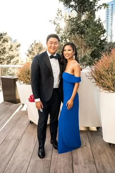 a man and woman standing next to each other on a wooden floor in formal wear