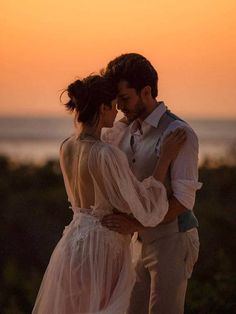 a man and woman standing next to each other at sunset