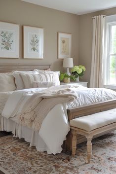 a white bed sitting in a bedroom next to a window with two pictures on the wall