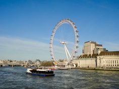 a large ferris wheel in the middle of a body of water with buildings around it