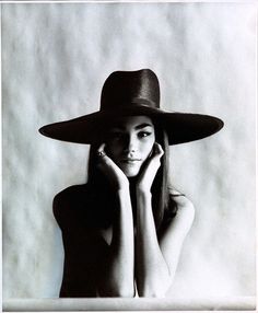 black and white photograph of a woman wearing a hat with her hands on her face