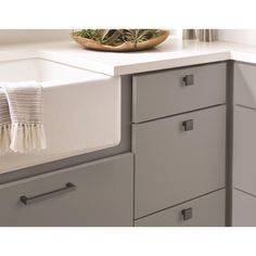 a dish towel is hanging on the edge of a kitchen sink with gray cabinets and drawers