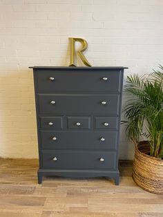 a black dresser with gold letters on it and a potted plant next to it