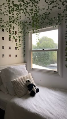 a stuffed animal sitting on top of a white bed in a bedroom next to a window