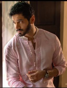 a man in a pink outfit standing next to a door and looking at the camera