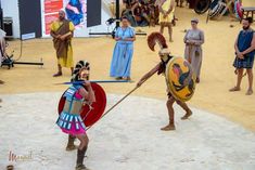 people dressed in roman costumes and holding spears