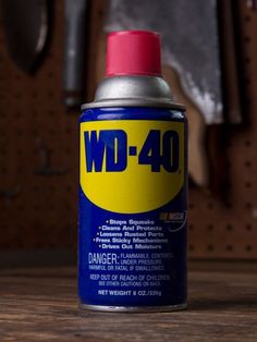 a can of wd - 40 sits on a table next to a wrench