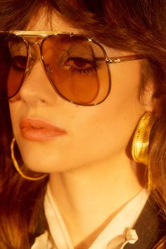 a close up of a person wearing some kind of gold earring and eyeglasses