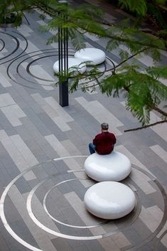 a person sitting on top of a white circular object in the middle of a courtyard