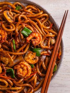 stir fry noodles with shrimp and vegetables in a bowl with chopsticks on the side