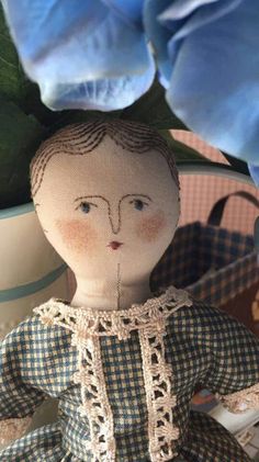 an old doll sitting next to a blue flower