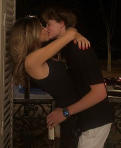 two people kissing each other outside at night