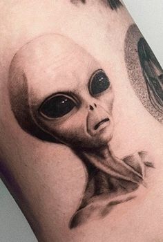 an alien head tattoo on the arm