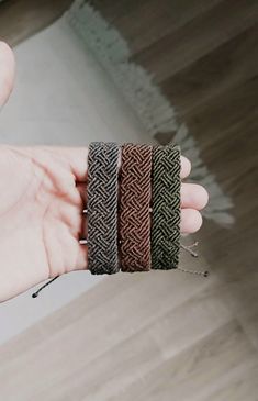 a person holding three different colored bracelets in their hand and one is wearing a ring