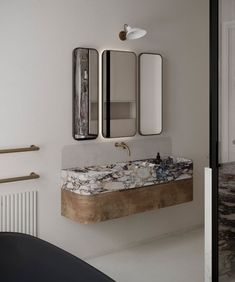 a bathroom sink sitting under two mirrors next to a radiator in a room