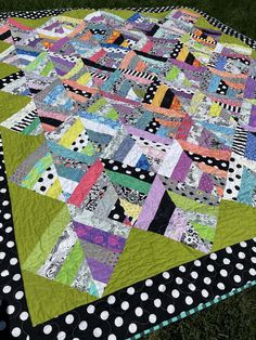 a quilt is laying on the grass with polka dotty trimmings and black, white, and green colors