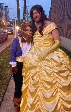 a man and woman dressed up as princesses pose for a photo on the sidewalk