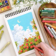 a person is drawing flowers with crayons on the table next to some markers