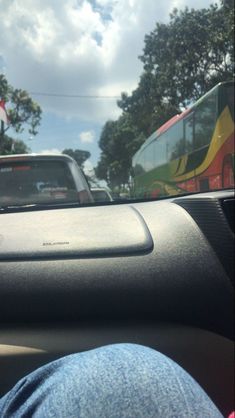 the dashboard of a car with a bus in the background and someone's feet on the dash