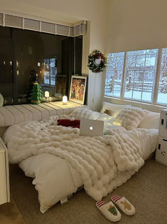 a bed covered in white blankets and pillows with a laptop on it's side