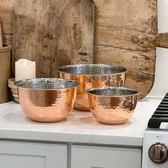 three metal bowls sitting on top of a white counter next to a burner oven