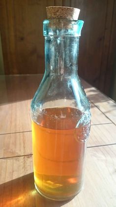 a glass bottle filled with liquid sitting on top of a wooden table