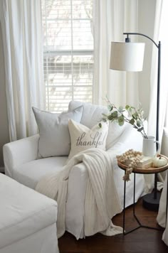 a living room with white furniture and pillows