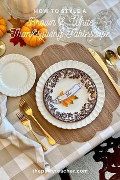 a table set for thanksgiving dinner with white and brown plates, silverware and pumpkins