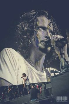 a man with long curly hair holding a microphone to his ear and wearing a white t - shirt