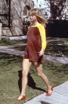 a woman walking down the sidewalk in her red and yellow dress with orange sleeves on