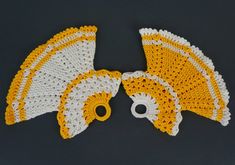 two yellow and white crocheted doily with holes in the middle on a black surface