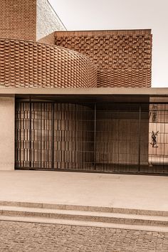 an empty parking lot next to a building with large doors and brickwork on it