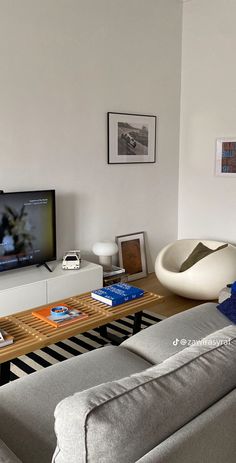 a living room with a couch, coffee table and flat screen tv on the wall