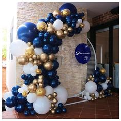 the balloon arch is decorated with blue, white and gold balloons