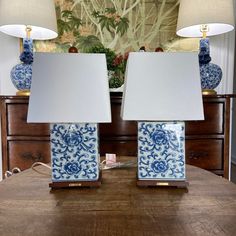 two blue and white vases sitting on top of a wooden table next to lamps