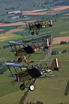 four airplanes are flying in formation over the countryside