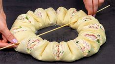 two hands are holding sticks to pull up some food wrapped in rolls on a black surface