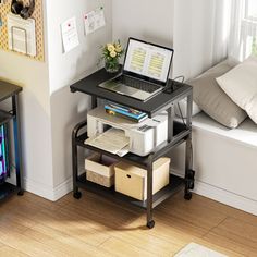 a laptop computer sitting on top of a wooden table next to a window sill