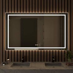 a bathroom sink with a lighted mirror above it and a potted plant on the counter