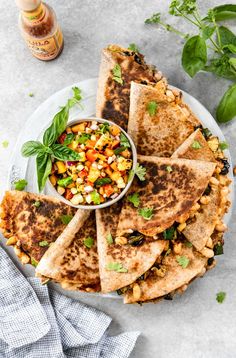 mexican quesadillas with corn and salsa on a plate next to a bottle