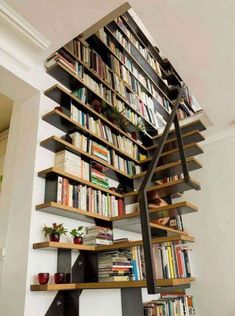 a bookshelf filled with lots of books next to a stair case