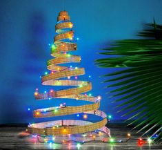 a christmas tree made out of wicker with lights on it and a palm tree in the background