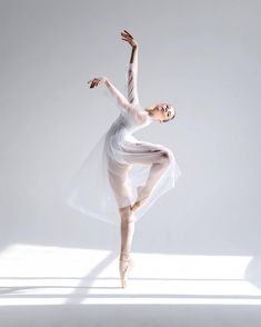 a ballerina in white is posing with her arms stretched out and legs bent forward