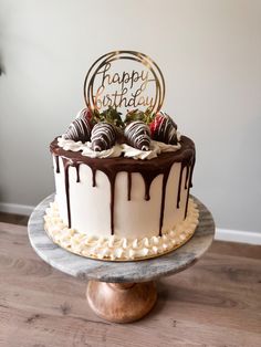 a birthday cake with chocolate and strawberries on top is sitting on a wooden table