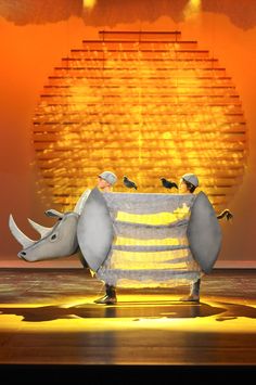 two people are standing in front of an elephant and rhinoceros on the stage