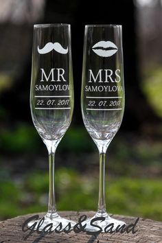 two personalized wine glasses sitting on top of a piece of wood with grass in the background