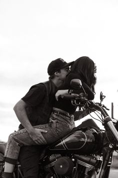 a man kissing a woman on the back of a motorcycle