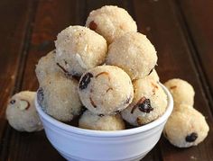 a white bowl filled with cookies sitting on top of a wooden table covered in nuts