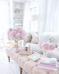 a living room filled with furniture and pink flowers on top of it's coffee table