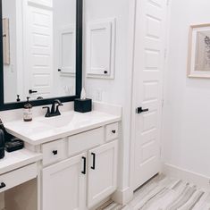 a bathroom with white cabinets and black accents